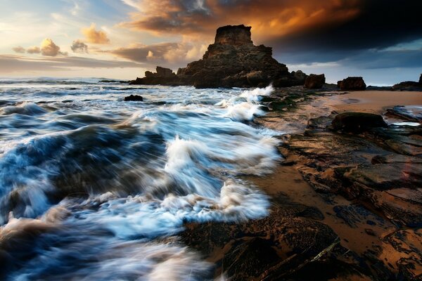 Sunrise on a rocky beach washed by the sea