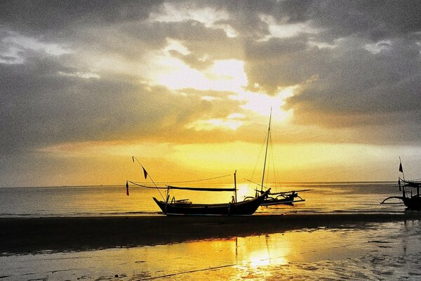 Image of the sea with a boat on the background of sunset