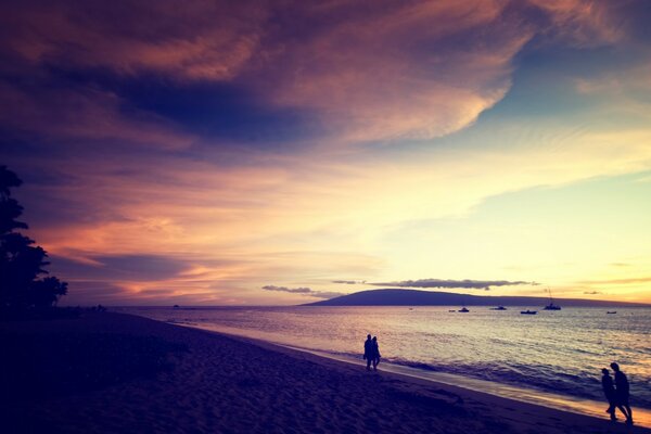 Casal andando na praia durante o pôr do sol