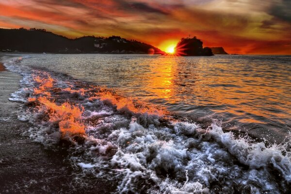 Pôr do sol vermelho na praia à beira-mar