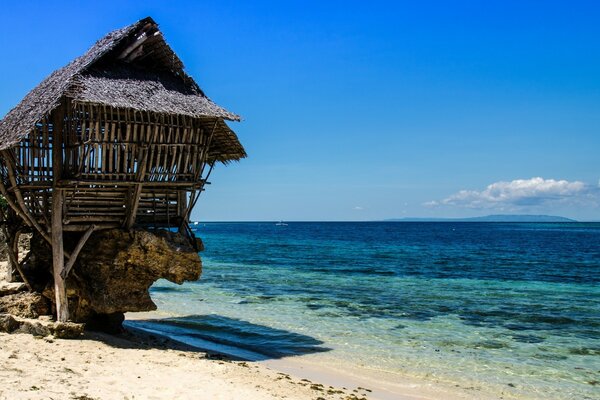 An old hut on the background of the ocean and tropical sand