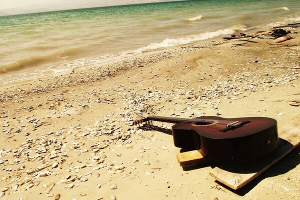 Und jemand hat die Gitarre am Meer am Sand vergessen