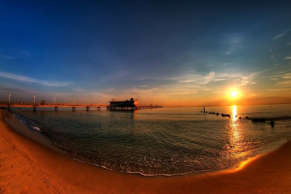 Photo of the beach on a wide-angle format with a pier