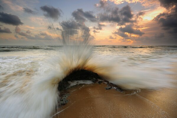 Coucher du soleil. Plage de sable et vagues de mousse