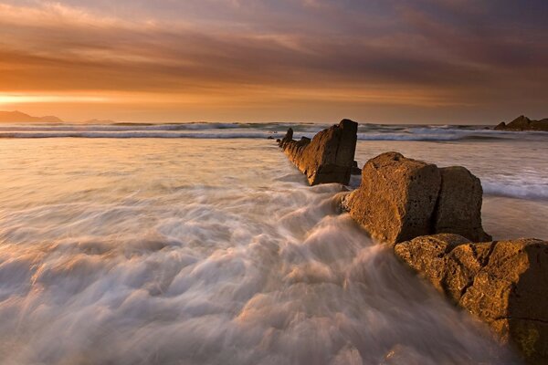 El océano se estrella contra grandes rocas al atardecer