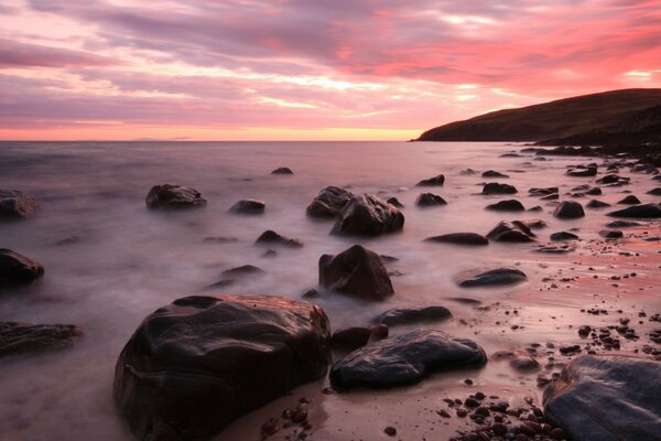 Large boulders in the sea foam at sunset