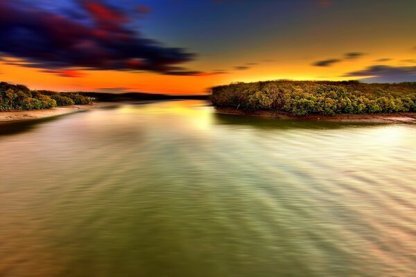 Fluss bei Sonnenuntergang. Die Insel. Der Strand