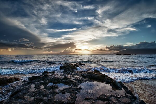 Olas de mar ligeras. Puesta de sol y nubes