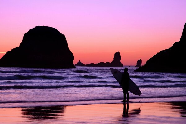 Surfer vor dem Hintergrund des purpurroten Himmels und des Meeres