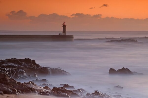 Faro en el mar en medio de la puesta de sol