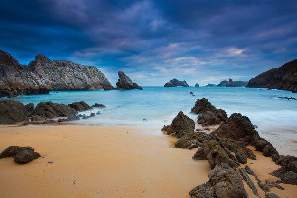 Praia de areia com montanhas e céu