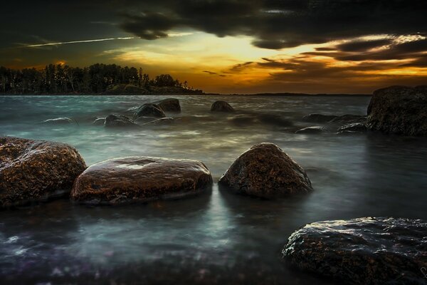 Falésias costeiras e Ilha do mar à distância contra o pôr do sol