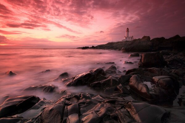 A lonely lighthouse against the pink evening sky