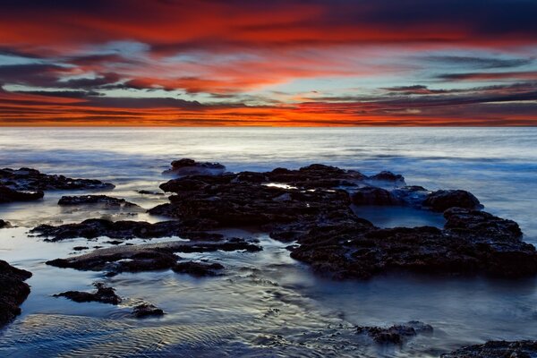 El frío amanecer del mar ilumina enormes rocas en la costa