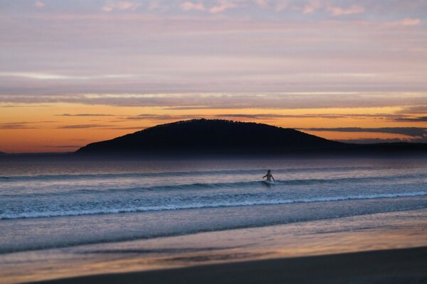 Einsamer Surfer im Meer bei Sonnenuntergang