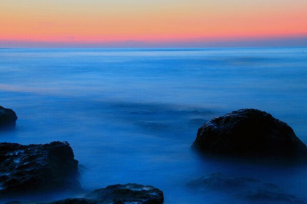 Calma, fría superficie azul del mar y rosa amanecer