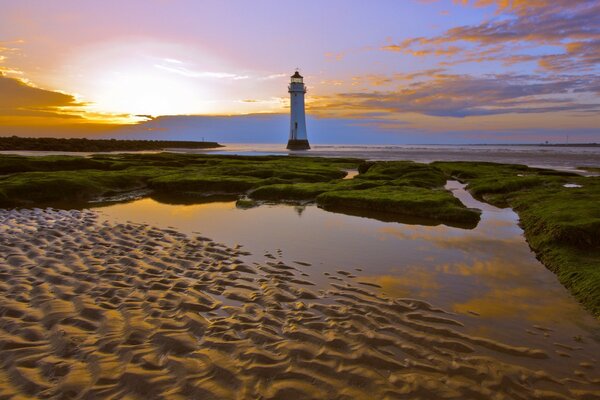 Ein einsamer Leuchtturm, der bei Sonnenuntergang von Wasser und grüner Vegetation umgeben ist