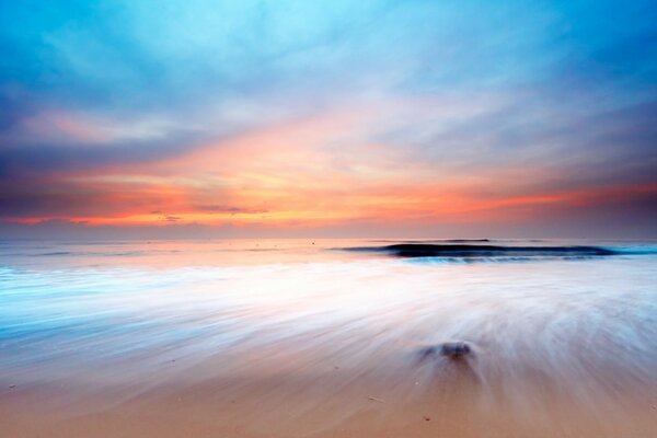 A beach with clear water and a beautiful sky