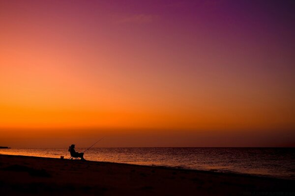 Costa del mar y puesta de sol. Hombre en la orilla