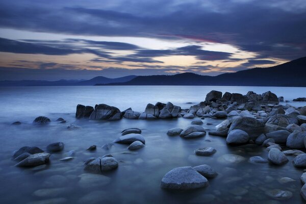 岩石海滩，日落的天空，轻雾在水面上