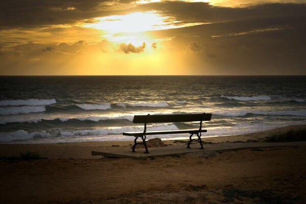 Banco vacío en el fondo de la puesta de sol del mar