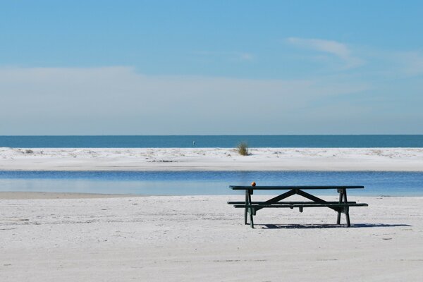 A bench on a sandy beach against the background of waves