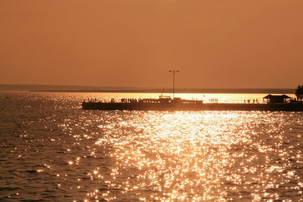 Pôr do sol no mar em tons de laranja, cais