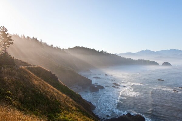 The waves are beating against the rocks in the rays of dawn