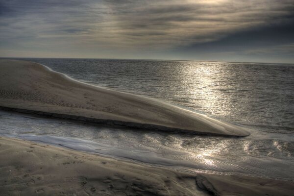 A deserted sandy beach washed by the sea under a cloudy sky