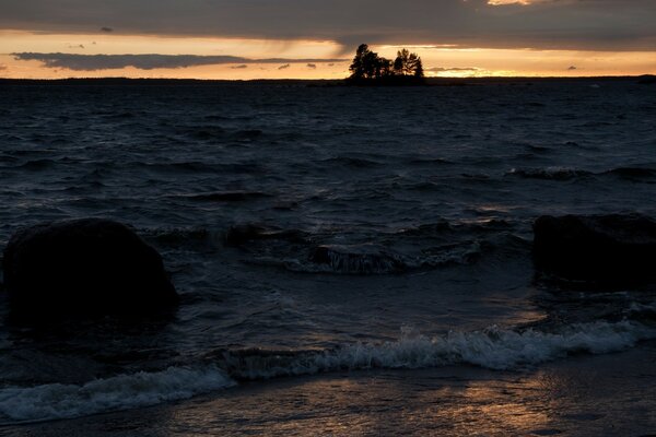 A restless sea against the background of a couple of trees and clouds