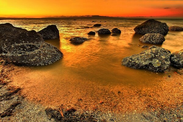 Bassa marea con pietre sul mare al tramonto