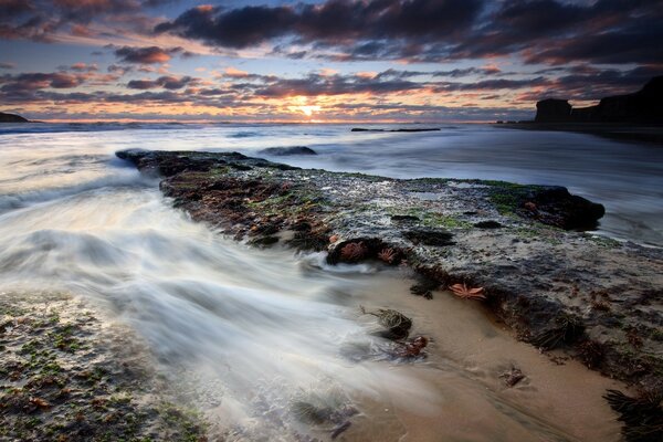 El agua de mar no tranquila lava la playa rocosa