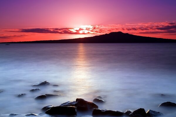 Heller Sonnenuntergang am Meer und Steine im Wasser