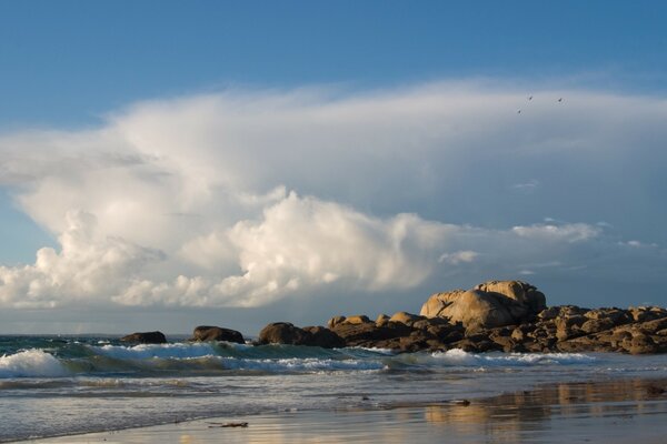 Ondas em uma costa arenosa contra um fundo de nuvens