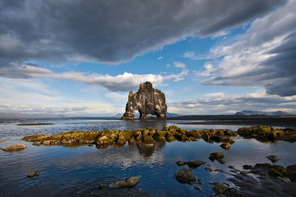 Enormes rocas sobresalen del agua de mar que refleja el cielo