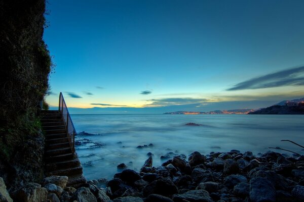 Treppe in blau-blaue Wellen des Meeres bei Sonnenuntergang