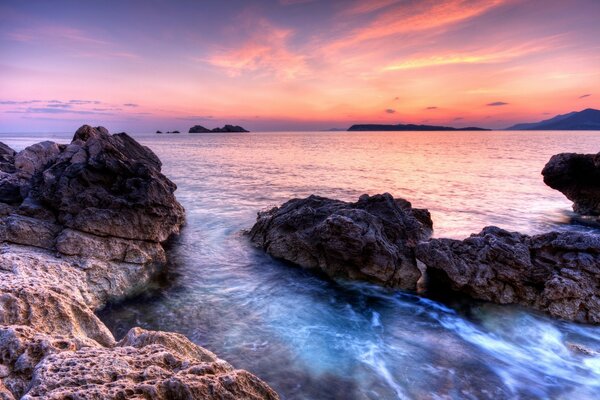 Rosa Sonnenuntergang über dem Meer und den Felsen 