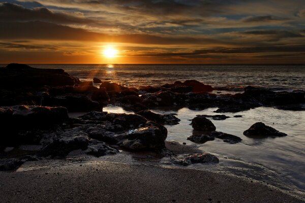 Puesta de sol en la costa rocosa del océano