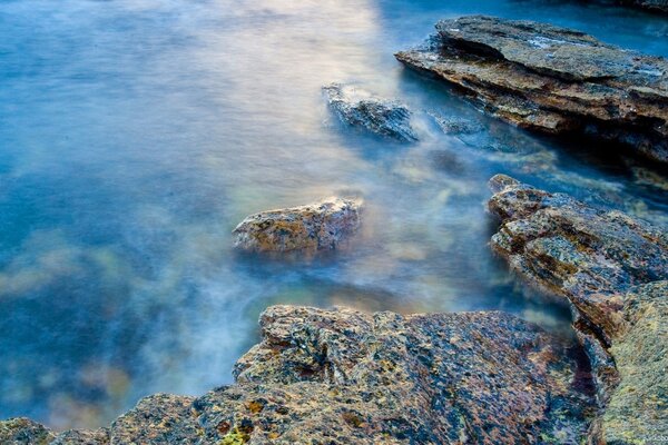 Transparent ocean with rocks in the fog