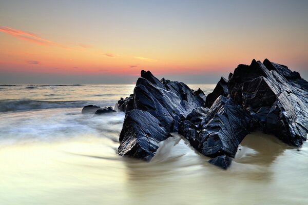 Las olas cortan las rocas negras