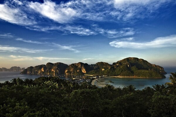 美丽的风景与山和绿树在日落时的海两岸