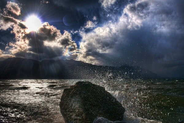 Spruzzi delle onde dell oceano attraverso i raggi del sole