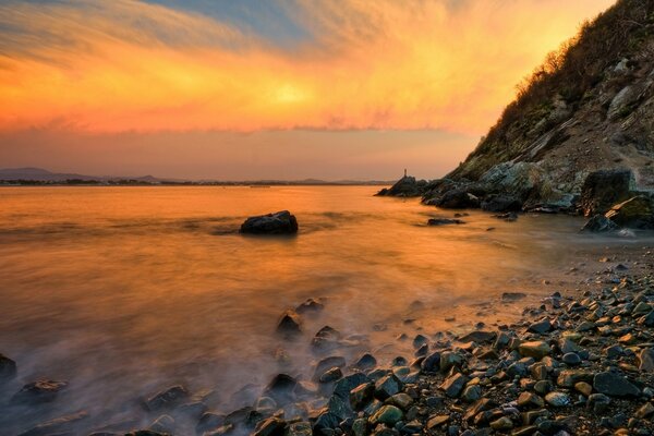 Landscape of mountains , ocean , rocks and fiery sunset