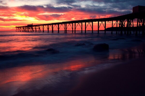 A bridge on the background of the ocean and the sunset reflected in it