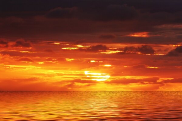 深红色的夕阳穿过云层在海洋上