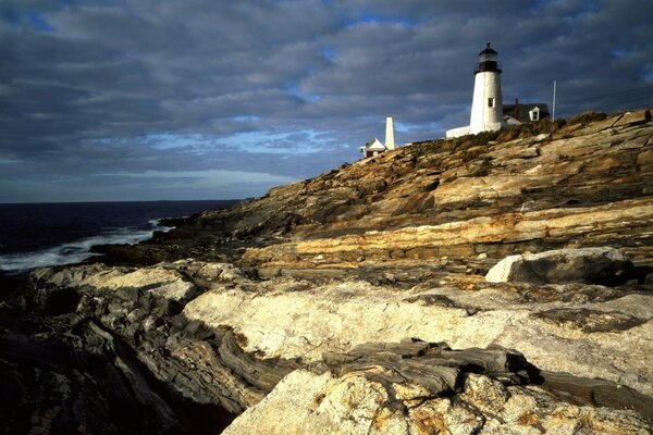 Lighthouse on the mountain and cloudy sky over the sea 