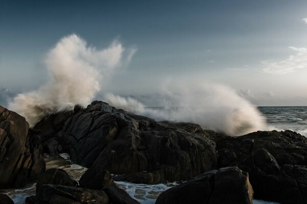 Les vagues de la mer se brisent sur les rochers avec beaucoup d éclaboussures