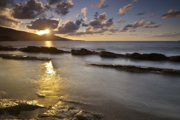 The sun appeared over the mountain, in front of which the water surface stretched