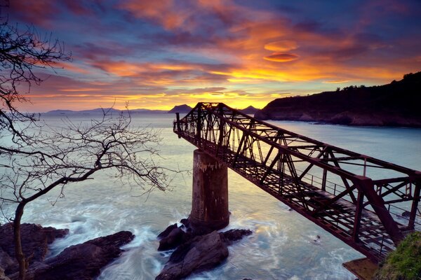 Brücke über dem Meer. Sonnenuntergang und Berge