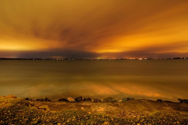 Sulla riva del Lago giallo sotto il cielo giallo al tramonto, e su quel lato una città luminosa